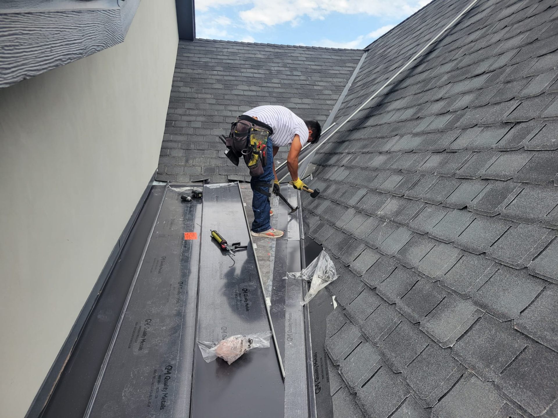 Trabajador instalando flashing metálico en techo de shingles